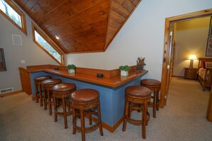 Zona de bar con taburetes de madera y una pared azul de acento.