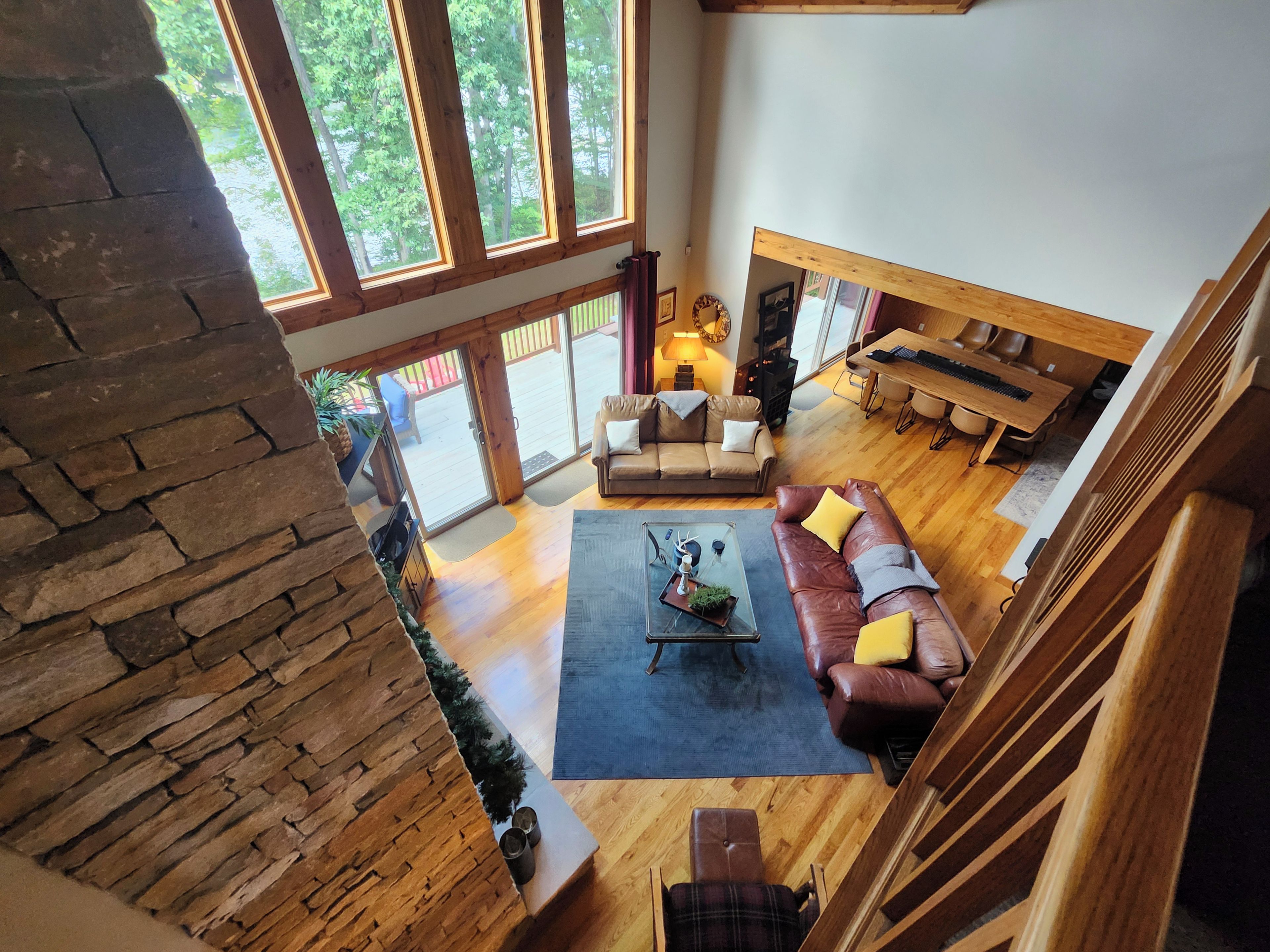 A spacious living area with a stone wall, a wooden staircase, and a view of the outdoors.