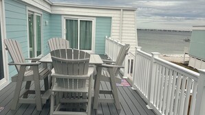 A deck with Adirondack chairs and a table, overlooking a body of water. -  Island's End Welcomes You to Paradise!   (Pensacola Beach)