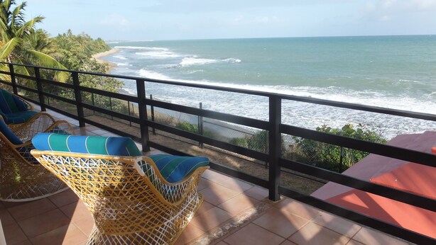 A balcony with wicker chairs and a view of the ocean. - Caribbean Beach Front Gem 2 (Punta Pozuelo, Guyama)