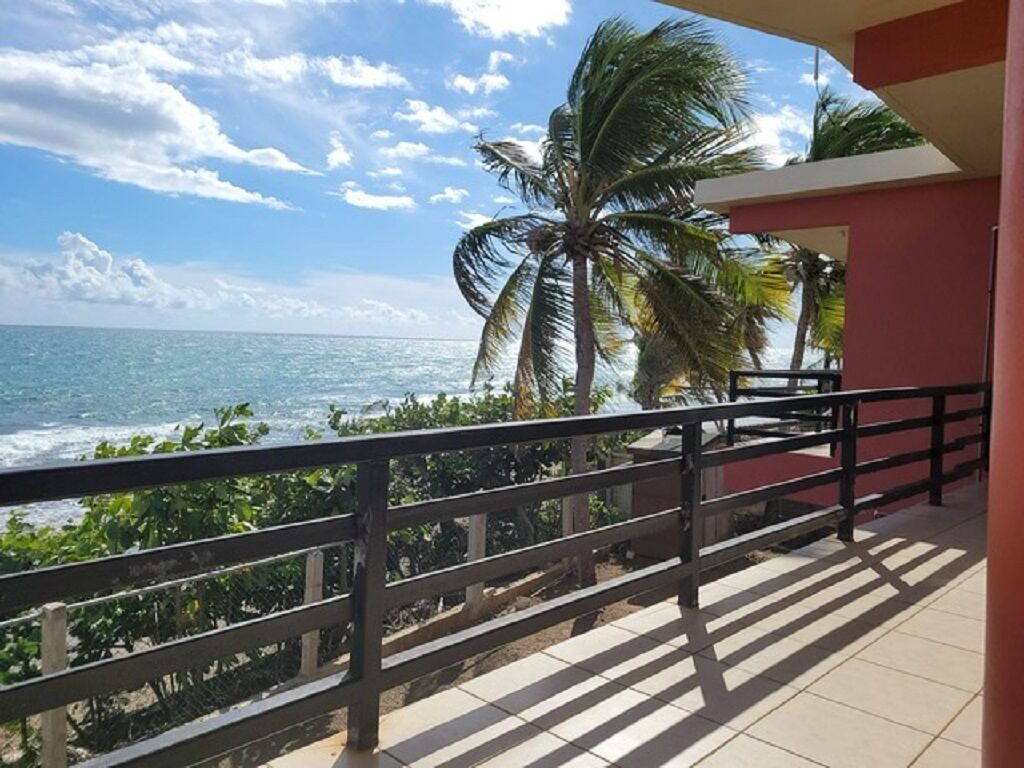 Een balkon met uitzicht op de oceaan en palmbomen.