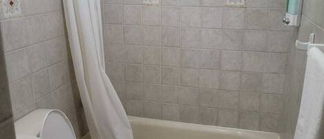 A bathroom with a toilet, bathtub, and shower curtain.