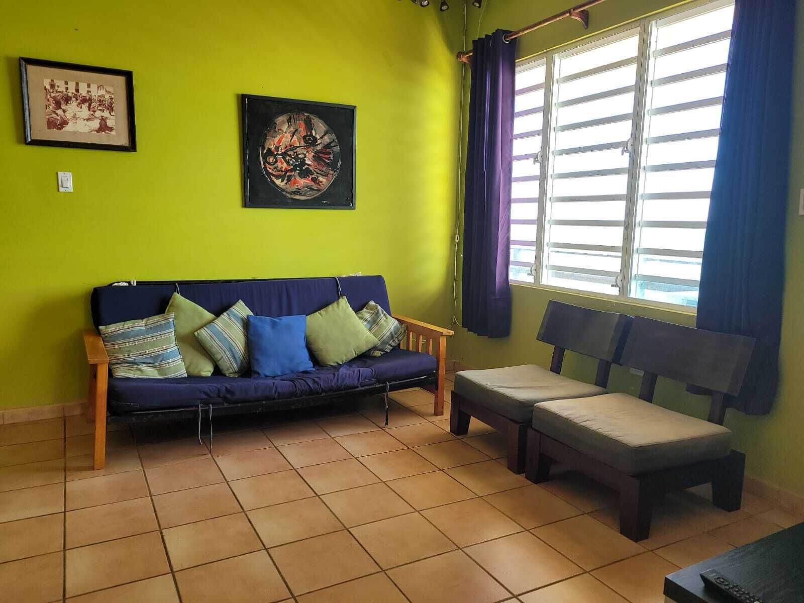 A room with a blue sofa, a wooden bench, and a window with curtains.