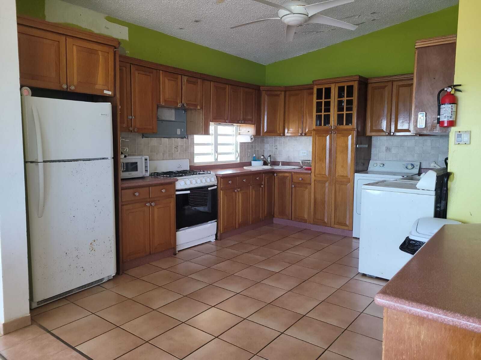 A kitchen with wooden cabinets, a white refrigerator, a microwave, an oven, a stove, and a washing machine.