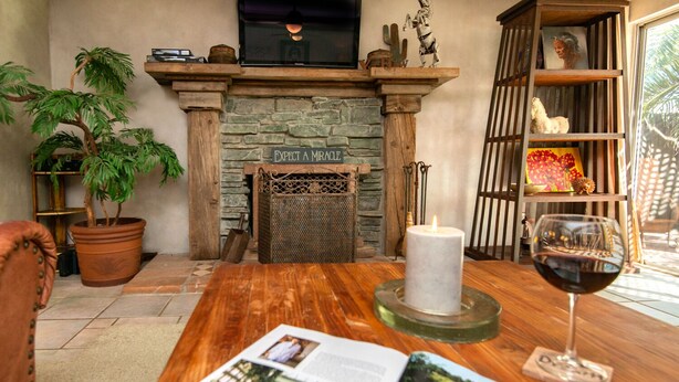 A cozy living room with a fireplace, a potted plant, a candle, and a glass of wine on a wooden table. - SUMMER Specials- Total Comfort close to Paradise Valley and Golf (Phoenix)