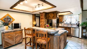 A kitchen with a central island, wooden chairs, a microwave, and a refrigerator. - SUMMER Specials- Total Comfort close to Paradise Valley and Golf (Phoenix)
