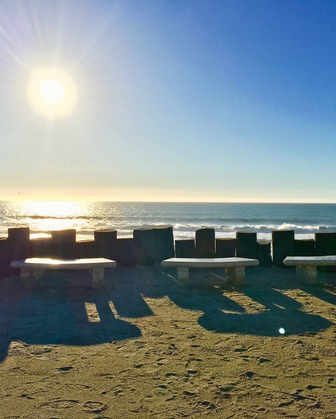 A beach with benches and a clear view of the ocean.