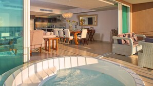 A modern living area with a dining table, chairs, a sofa, and a hot tub.