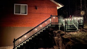 Une cabane en bois avec un escalier menant à une véranda, le tout entouré d’arbres.