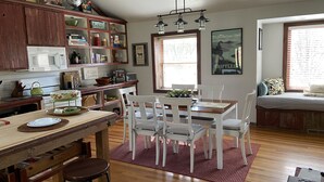 Une cuisine chaleureuse avec des meubles en bois, une table à manger entourée de chaises blanches et un tapis rouge.
