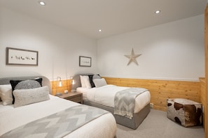A bedroom with two beds, a wooden headboard, a star decoration, and framed artwork on the wall.