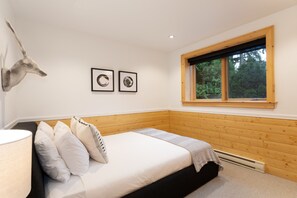 A bedroom with a bed, pillows, a headboard, a window, and two framed pictures on the wall. - Pinnacle Ridge 34 - Ski in Ski out, Private Hot Tub, Billiards, Fireplace (Whistler)
