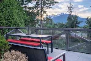 An outdoor seating area with a table and benches, overlooking a mountainous landscape.