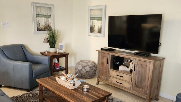 Una sala de estar con sofá, mesa de centro, televisor y aparador.