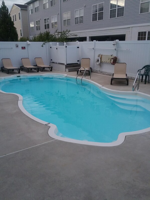 A swimming pool with lounge chairs and a white fence. - Great Location! Lots of Amenities! (Wildwood)