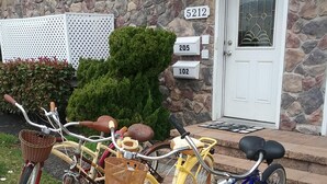 Tres bicicletas estacionadas frente a una casa de fachada de piedra y puerta blanca.