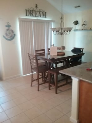 A dining area with a table and chairs, a chandelier, and a sign that reads "DREAM" on the wall. - Great Location! Lots of Amenities! (Wildwood)