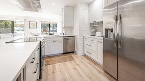 A modern kitchen with white cabinetry, stainless steel appliances, and a large island.