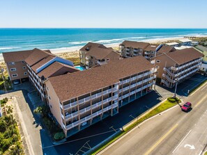 A multi-story hotel with a parking lot and a view of the beach.