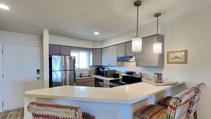 A modern kitchen with a central island, stainless steel appliances, and bar stools.