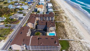 An aerial view of a coastal hotel with multiple buildings, a beach, and a road.