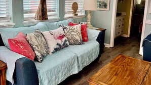 A living room with a light blue couch, wooden coffee table, and a whale tail decoration on the wall. - CLOSE TO THE OCEAN ocean lakes site 1048 golf cart Pet friendly (Myrtle Beach)