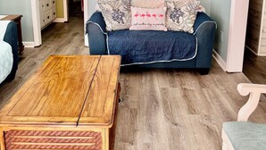 A living room with a blue sofa, a wooden coffee table, and three framed pictures of a beach scene. - CLOSE TO THE OCEAN ocean lakes site 1048 golf cart Pet friendly (Myrtle Beach)