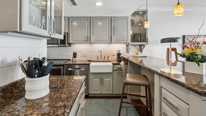 Una cocina moderna con encimeras de granito, electrodomésticos de acero inoxidable y horno empotrado.