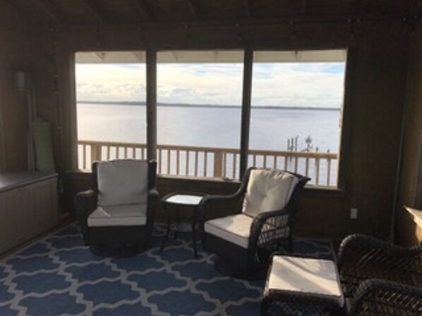 Enjoy the serene view of the water from the comfort of your room, featuring a seating area with a table and wicker chairs.