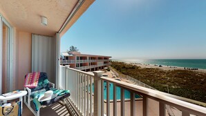 A balcony with a view of the beach and a pool.