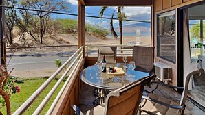 Ein Balkon mit Tisch für zwei Personen, mit Blick auf eine Straße und einen Strand.