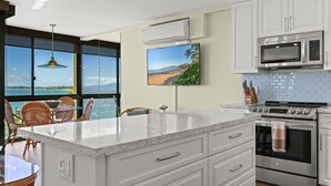 A modern kitchen with white cabinets, a large island, a microwave, and an oven. - 605 - Top Floor, Luxury Oceanfront, Newly-renovated with A/C!  1/1.5 (Kihei)
