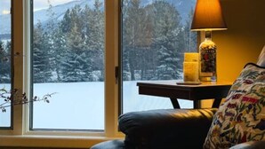 Een kamer met een groot raam dat uitzicht biedt op een besneeuwd berglandschap.
