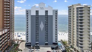 A hotel with a prominent logo, multiple floors, and a view of the beach.