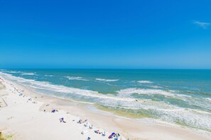 Ein Strand mit weitem, sandigen Ufer und sanften Wellen.