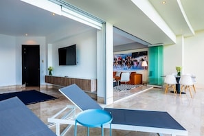 Eine moderne Hotelhalle mit großem Fernseher, Sitzgelegenheiten und einer Glastrennwand.