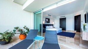 A modern hotel room with a bed, a desk, and a seating area with chairs and a small table.