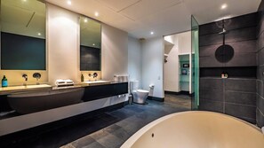 A modern bathroom with a large bathtub, a double sink vanity, and a toilet.