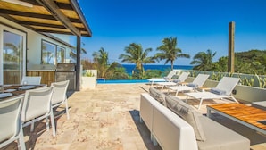 Une terrasse avec une piscine, des chaises longues et un coin cuisine équipé d’un barbecue.