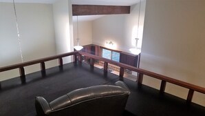 Een ruim balkon met een leren bank, houten leuning en uitzicht op een stenen gebouw.