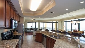 A spacious kitchen with granite countertops, stainless steel appliances, and a large island with a sink. - Best Prices for 4 BR Corner Unit! (Orange Beach)