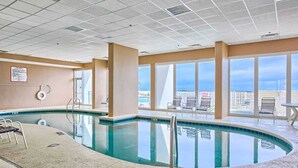 En indendørs swimmingpool med frit udsyn til byens skyline gennem store vinduer.
