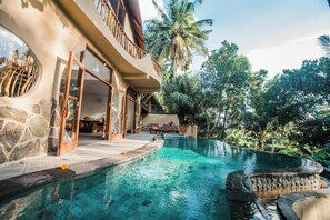 A modern house with a swimming pool, stone walls, and a balcony. - 5BR NAUTILUS TREE HOUSE Private Quiet amid Rice Field and Nature (Ubud)