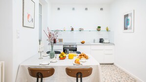 Eine moderne Küche mit weißen Schränken, einem für das Frühstück gedeckten Esstisch und einer gefliesten Spritzschutzwand.