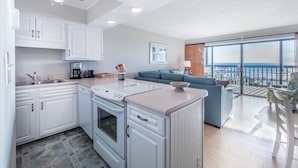 A modern kitchen with white cabinets, a built-in oven, and a countertop with a coffee maker. - Sea Colony 21B | Oceanfront, Private Beach Walkway (Carolina Beach)