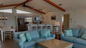 A spacious living room with a light blue sofa set, a wooden coffee table, and a kitchen area in the background. - Beachfront, Plantation, Pet Friendly (Eastpoint)