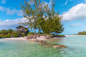 A beachfront property with a wooden structure, clear turquoise waters, and lush greenery. - The Lodge at Parrot Cay, TCI (Caicos Islands)