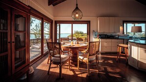 A spacious dining area with a large wooden table, wicker chairs, and a hanging light fixture. - The Lodge at Parrot Cay, TCI (Caicos Islands)