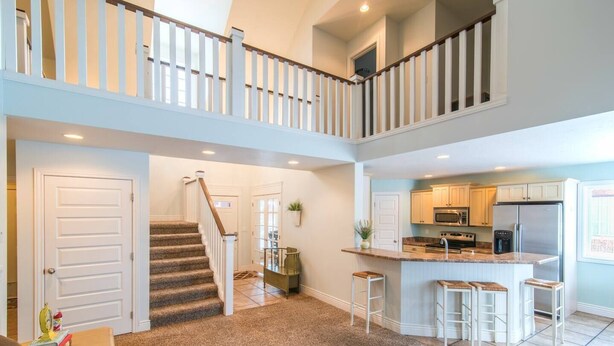 Un vaste espace de vie avec un escalier menant à un deuxième étage, une cuisine équipée d’appareils modernes et un coin bar.