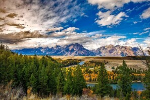 Un paysage montagneux avec un lac, une forêt dense et un ciel dégagé.